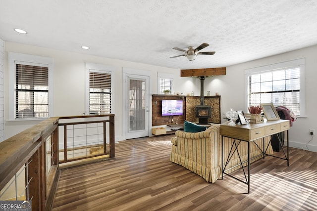 living room with a healthy amount of sunlight, dark hardwood / wood-style floors, a textured ceiling, and a wood stove