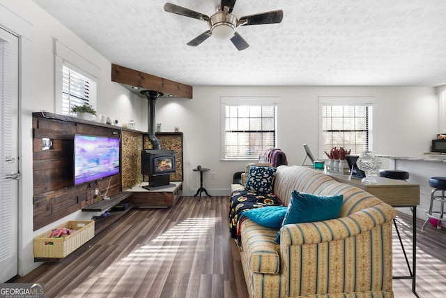 living room with a wealth of natural light, wood-type flooring, a textured ceiling, and a wood stove