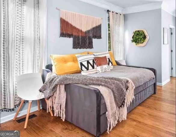 bedroom with crown molding and hardwood / wood-style floors