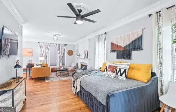 bedroom featuring hardwood / wood-style floors, crown molding, and ceiling fan