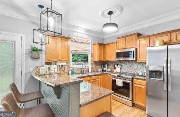 kitchen featuring sink, crown molding, hanging light fixtures, appliances with stainless steel finishes, and kitchen peninsula