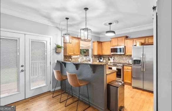 kitchen with a kitchen breakfast bar, hanging light fixtures, kitchen peninsula, stainless steel appliances, and french doors