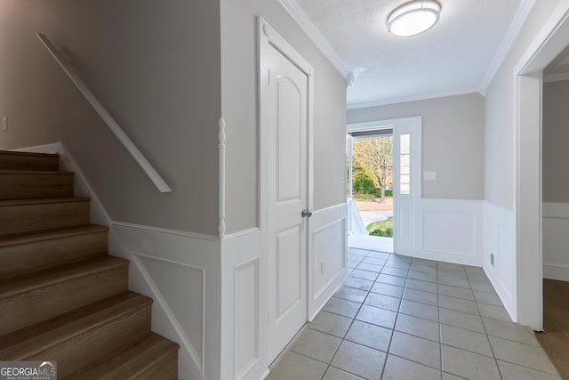 entryway featuring crown molding, a textured ceiling, and light tile patterned floors