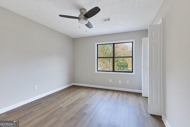 spare room featuring ceiling fan, light hardwood / wood-style flooring, and a textured ceiling