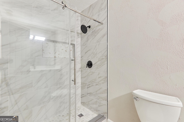 bathroom with a tile shower and toilet