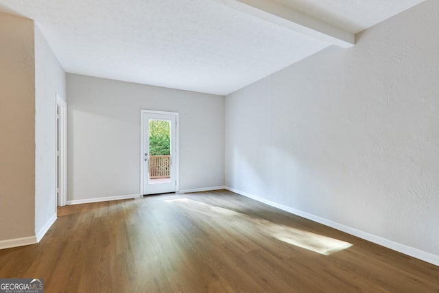 unfurnished room featuring beamed ceiling and wood-type flooring