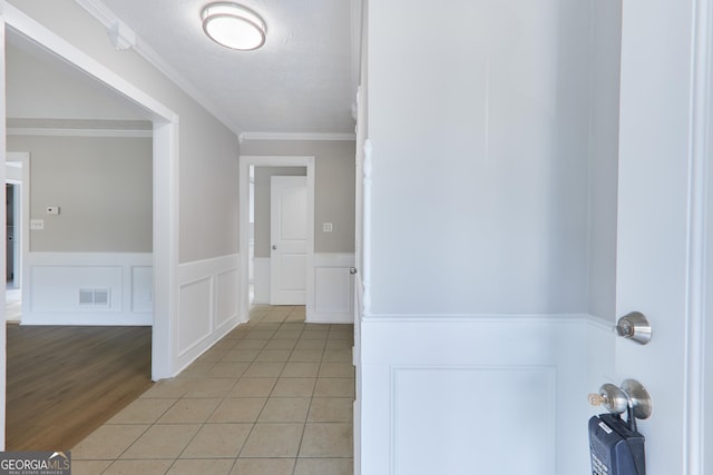 corridor with crown molding, light tile patterned flooring, and a textured ceiling