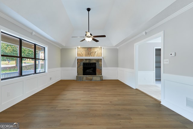 unfurnished living room featuring a stone fireplace, ornamental molding, ceiling fan, a tray ceiling, and dark wood-type flooring