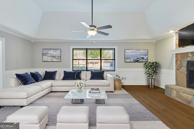 living room featuring hardwood / wood-style floors, a stone fireplace, ornamental molding, and a raised ceiling