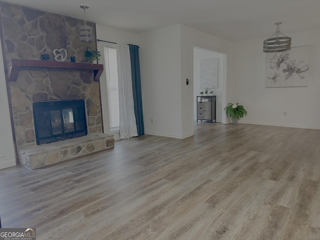 unfurnished living room featuring baseboards, a fireplace, and wood finished floors