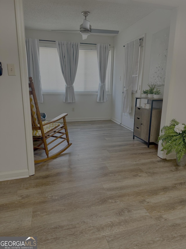 unfurnished room with baseboards, a textured ceiling, and wood finished floors
