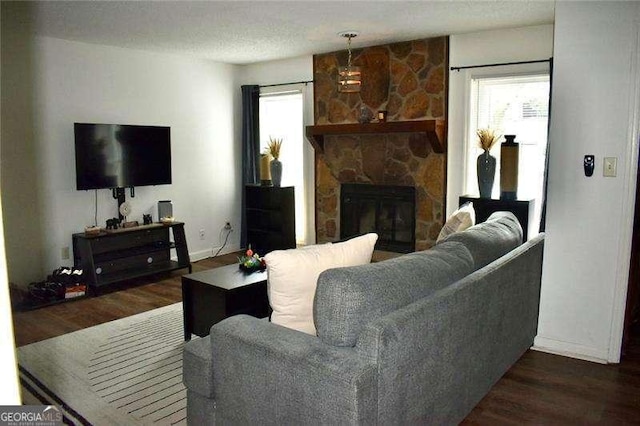 living room featuring dark wood-type flooring and a stone fireplace