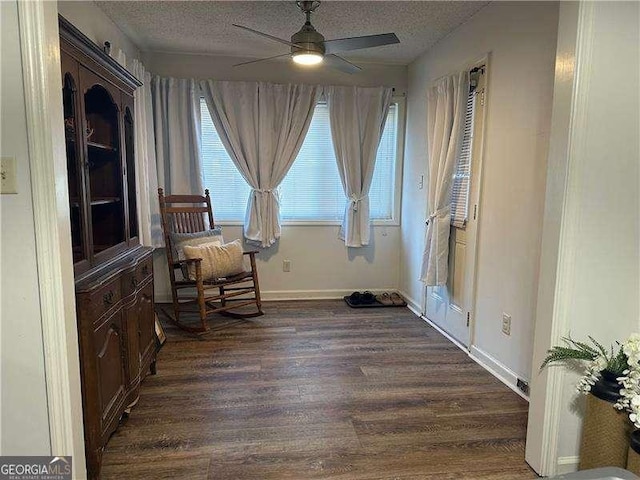 sitting room featuring ceiling fan, dark hardwood / wood-style floors, and a textured ceiling