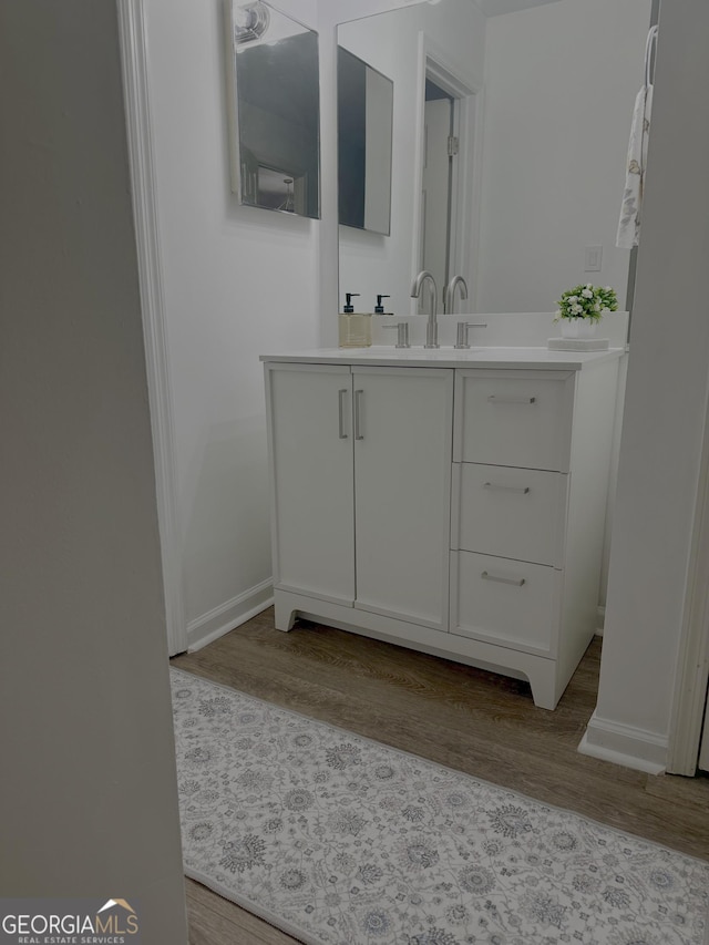 bathroom with baseboards, wood finished floors, and vanity