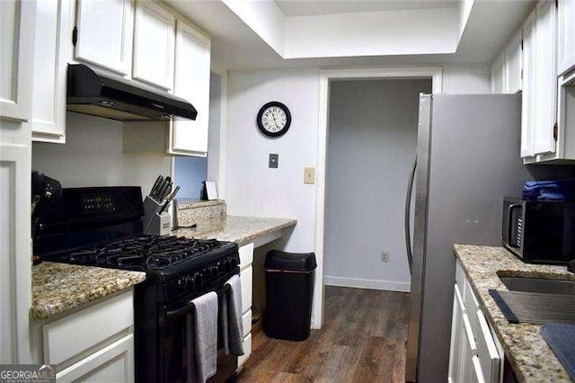 kitchen featuring light stone countertops, appliances with stainless steel finishes, dark wood-type flooring, under cabinet range hood, and white cabinetry