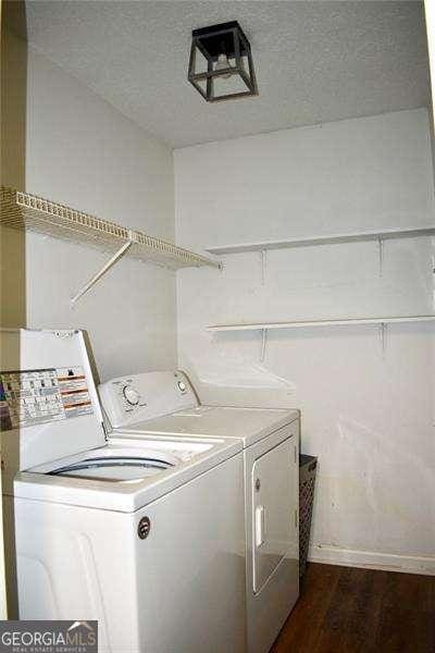 laundry area featuring washing machine and clothes dryer, a textured ceiling, laundry area, and dark wood finished floors