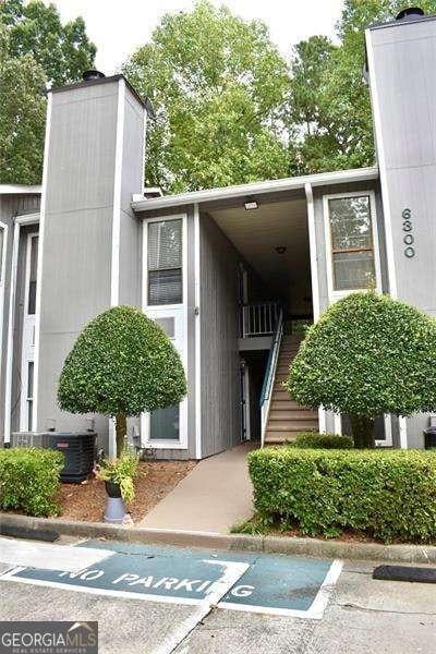 view of exterior entry with central AC, uncovered parking, and a chimney