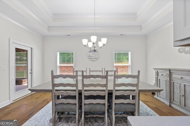 dining room featuring crown molding, hardwood / wood-style floors, a tray ceiling, and a chandelier