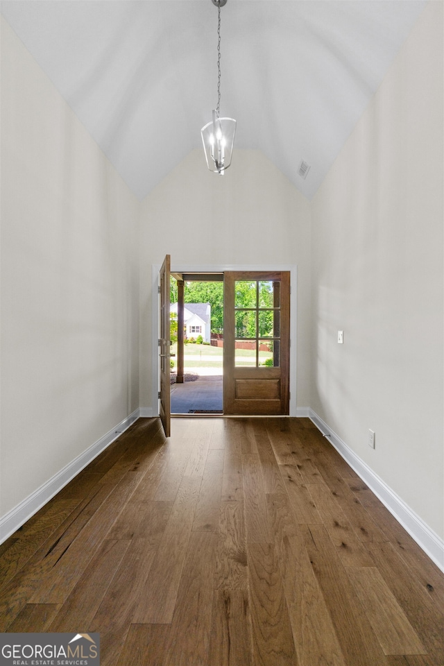 empty room with dark hardwood / wood-style flooring, vaulted ceiling, and an inviting chandelier