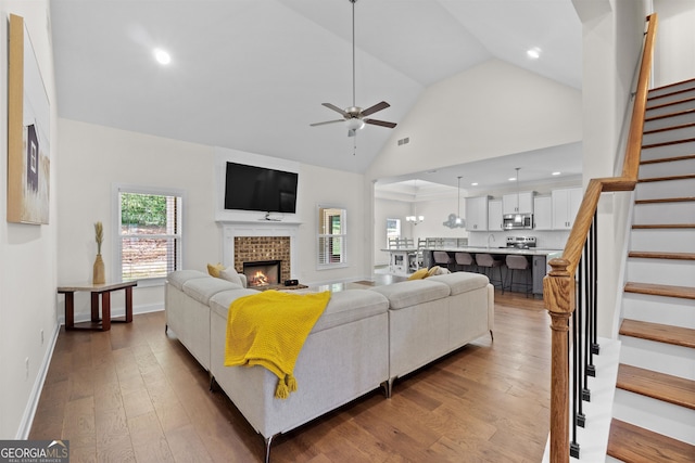 living room featuring ceiling fan, wood-type flooring, sink, and high vaulted ceiling