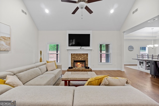 living room featuring wood-type flooring, ceiling fan with notable chandelier, and high vaulted ceiling