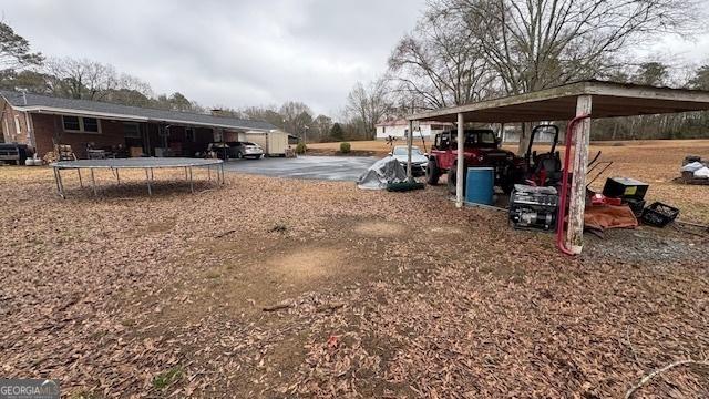 view of yard with a carport and a trampoline