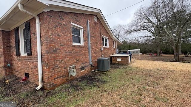 view of side of property with central AC unit and a yard