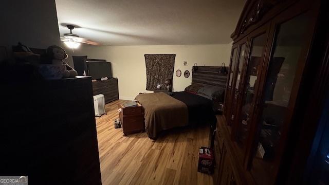 bedroom with radiator, ceiling fan, and light wood-type flooring