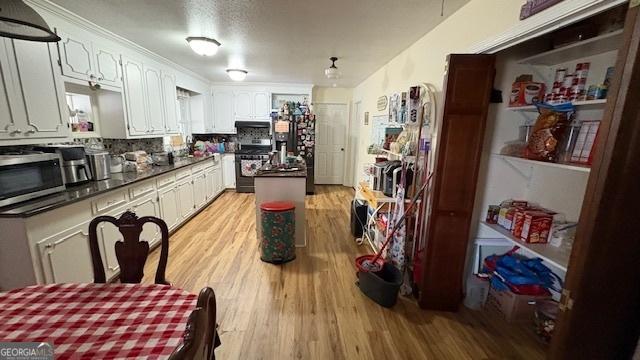 kitchen with tasteful backsplash, stainless steel appliances, light hardwood / wood-style floors, and white cabinets