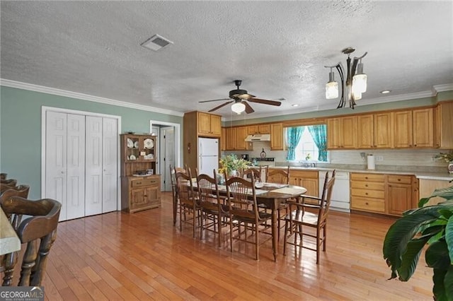 dining area featuring sink, ornamental molding, light hardwood / wood-style floors, a textured ceiling, and ceiling fan with notable chandelier