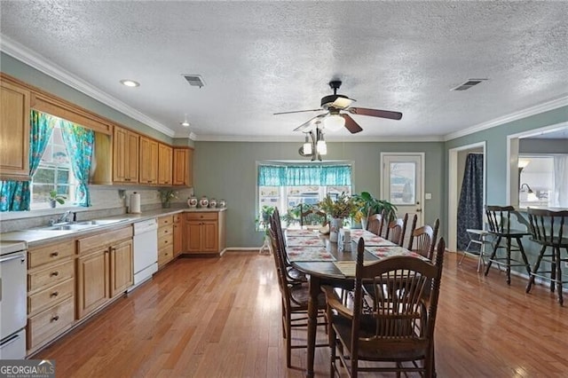 kitchen featuring white dishwasher, crown molding, plenty of natural light, and light hardwood / wood-style flooring