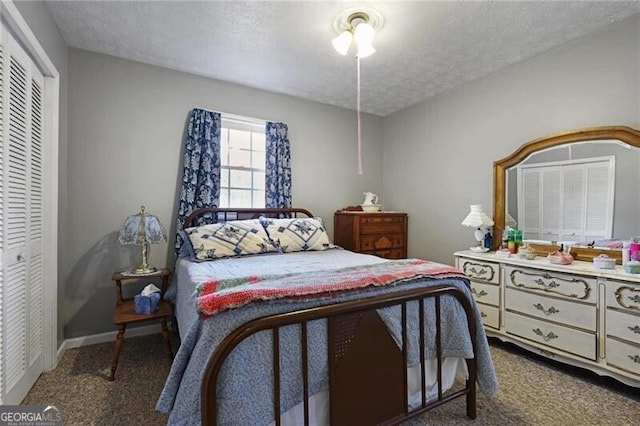 bedroom with dark colored carpet, ceiling fan, a closet, and a textured ceiling