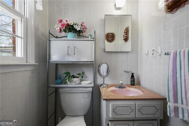 bathroom featuring vanity, tile walls, and toilet