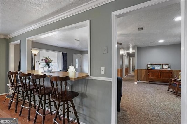 bar featuring ornamental molding and a textured ceiling