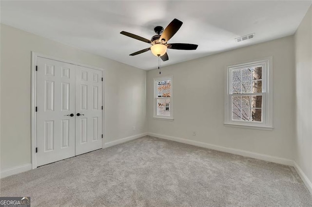 unfurnished bedroom featuring ceiling fan, light carpet, and a closet