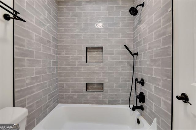 bathroom with tiled shower / bath and toilet