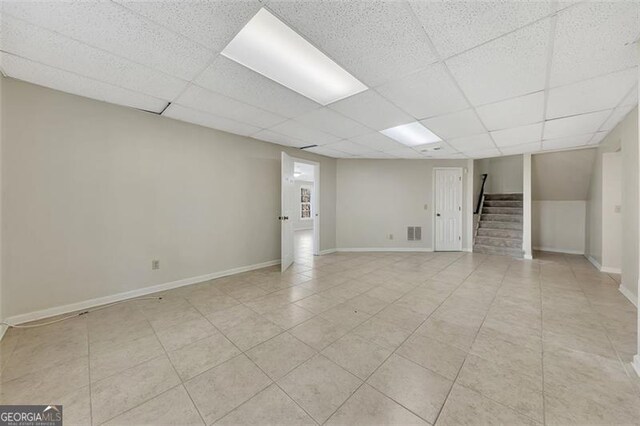 basement with light tile patterned flooring and a paneled ceiling