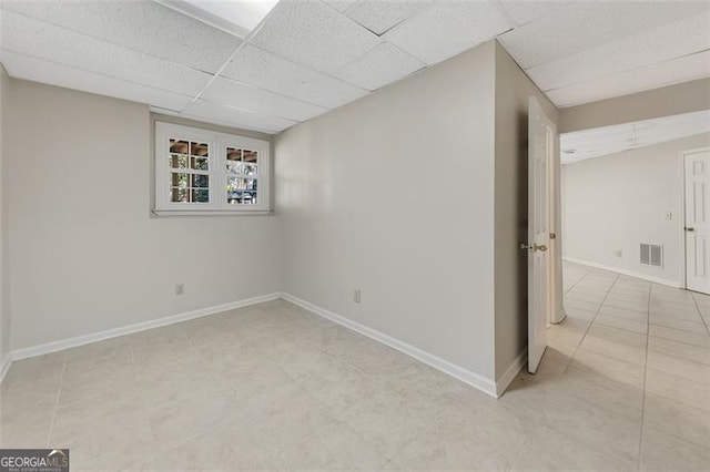 basement featuring light tile patterned floors and a drop ceiling