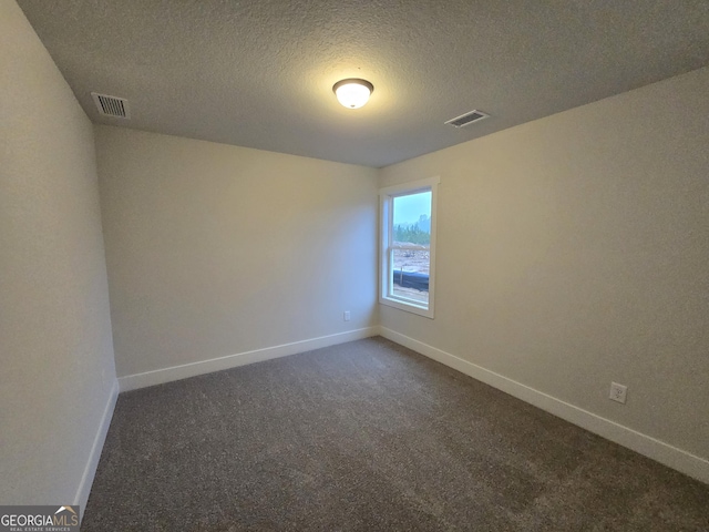 carpeted empty room featuring a textured ceiling