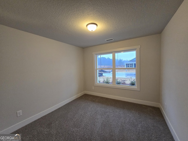 carpeted empty room with a textured ceiling