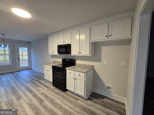 kitchen with light stone countertops, black appliances, white cabinets, and light wood-type flooring