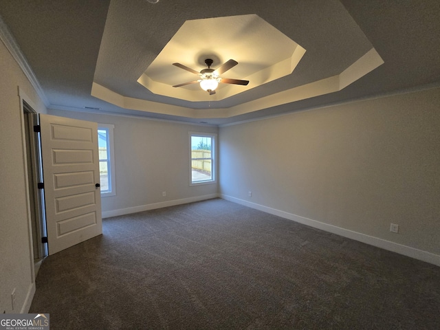 unfurnished room featuring dark colored carpet, crown molding, ceiling fan, and a tray ceiling