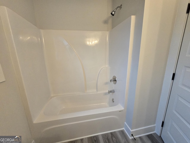 bathroom with wood-type flooring and washtub / shower combination