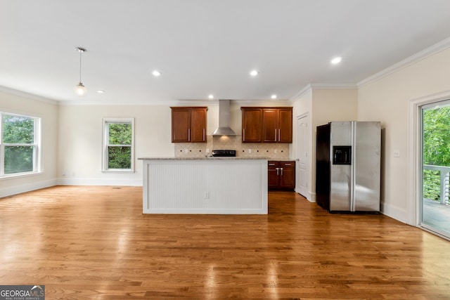 kitchen with hardwood / wood-style flooring, stainless steel refrigerator with ice dispenser, wall chimney range hood, and decorative backsplash