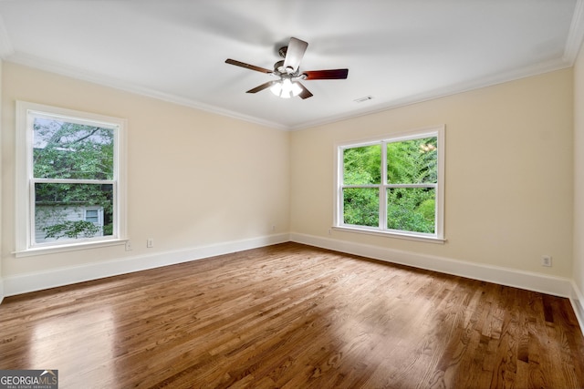 spare room featuring hardwood / wood-style flooring, ceiling fan, plenty of natural light, and crown molding