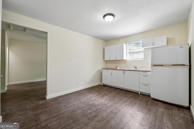 kitchen featuring white refrigerator, dark wood-type flooring, sink, and white cabinets