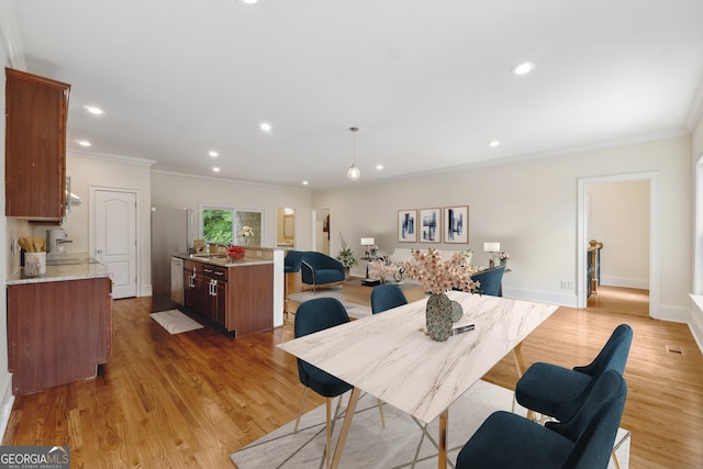 dining space featuring crown molding, sink, and light hardwood / wood-style floors