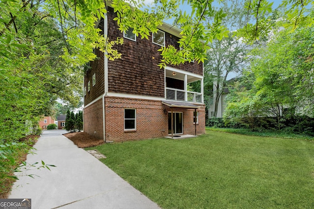 view of side of property featuring a balcony and a yard