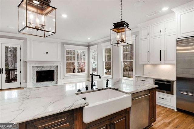 kitchen featuring crown molding, white cabinetry, hanging light fixtures, light hardwood / wood-style flooring, and appliances with stainless steel finishes