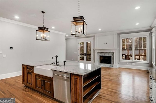 kitchen featuring an island with sink, stainless steel dishwasher, crown molding, and light hardwood / wood-style floors